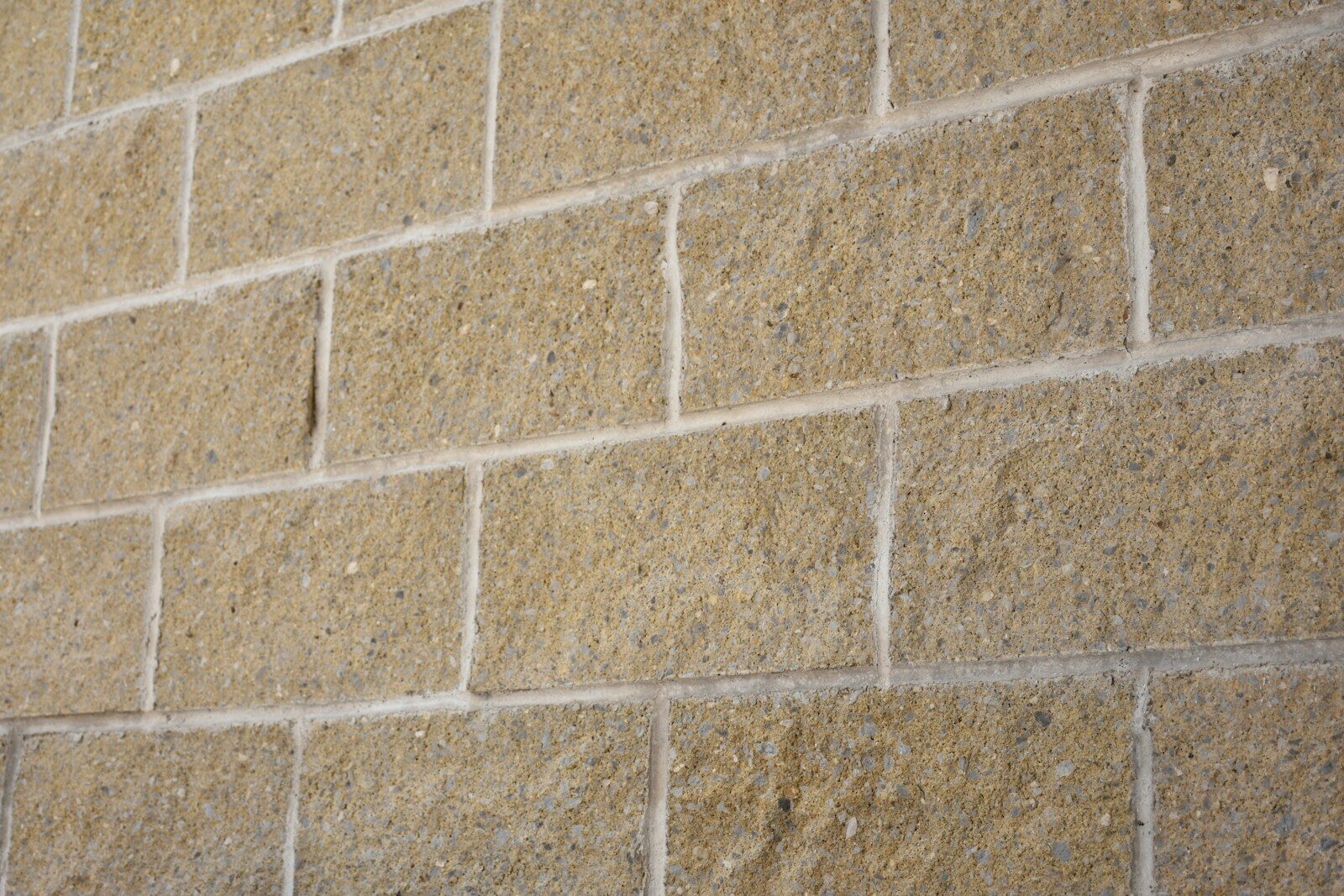 A tan brick wall with white grout